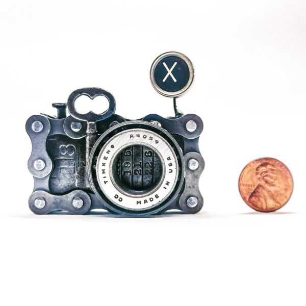 A camera with a penny next to it.