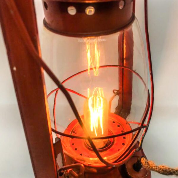 A Vintage Lantern converted to Desk Lamp with a light on it.
