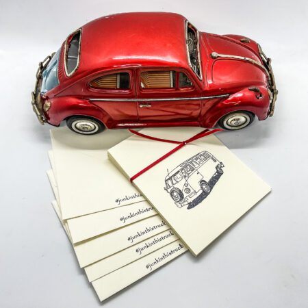 A red volkswagen beetle sits on top of a set of 6 Hand Stamped greeting Cards.
