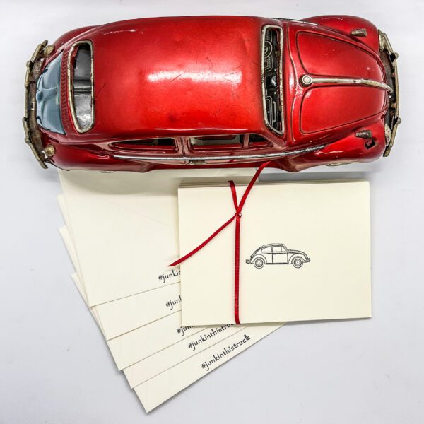 A red vw beetle sits on top of a set of 6 Hand Stamped greeting Cards.