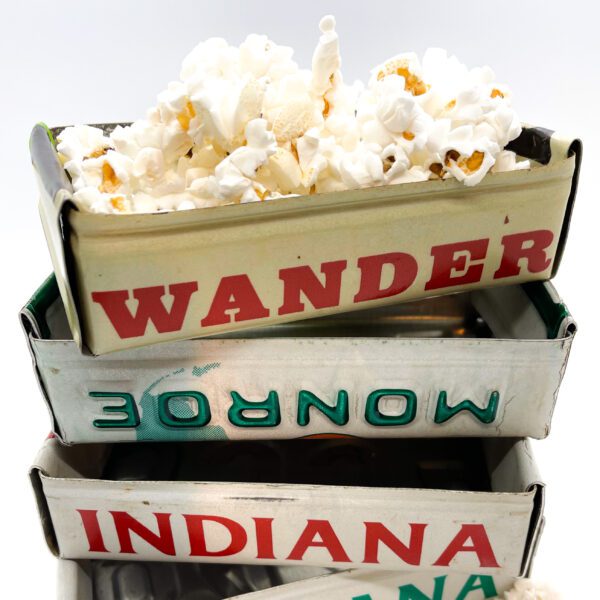 A stack of Vintage License Plate Valet Trays with popcorn in them.