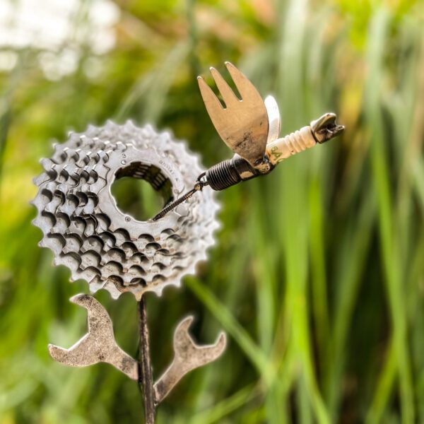 A bicycle gear Hummingbird garden sculpture with a bird on it.