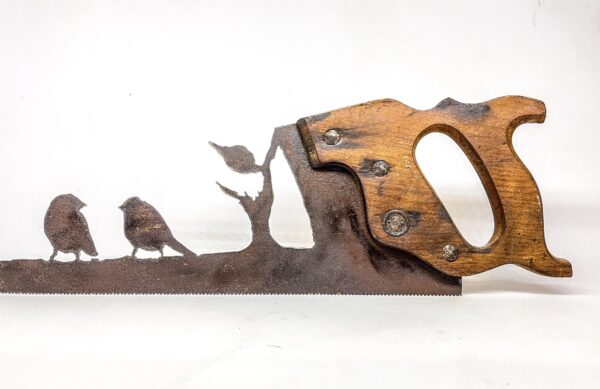 A pair of plasma cut saw-love birds on tree branch and a saw blade on a piece of wood.