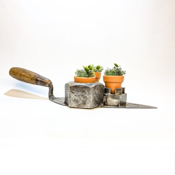 A Trowel succulent planter with potted plants and a shovel.